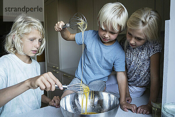 Geschwister bereiten in der heimischen Küche Kuchenteig zu