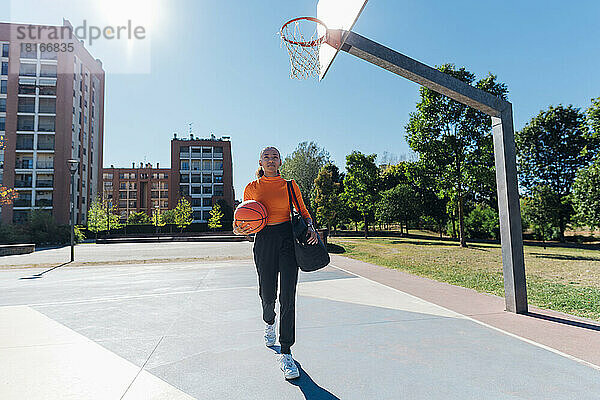 Junge Sportlerin läuft mit Basketball auf dem Sportplatz