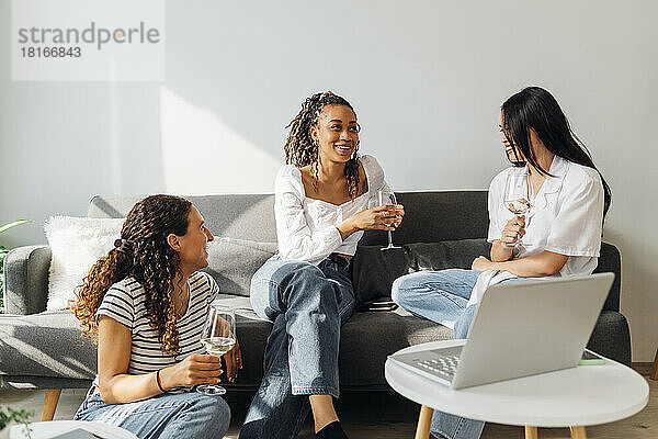Smiling roommates with wine talking in living room