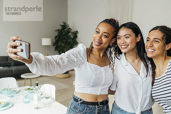 Smiling woman taking selfie with friends at home