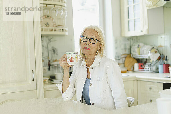 Frau hält Tasse in der Küche zu Hause