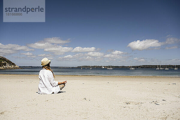 Reife Frau praktiziert Meditation am Strand