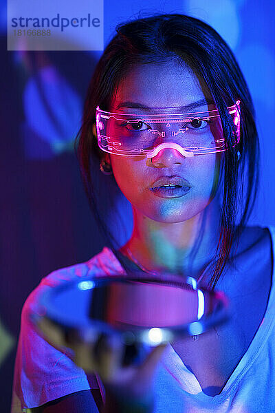 Young woman with smart glasses holding mirror