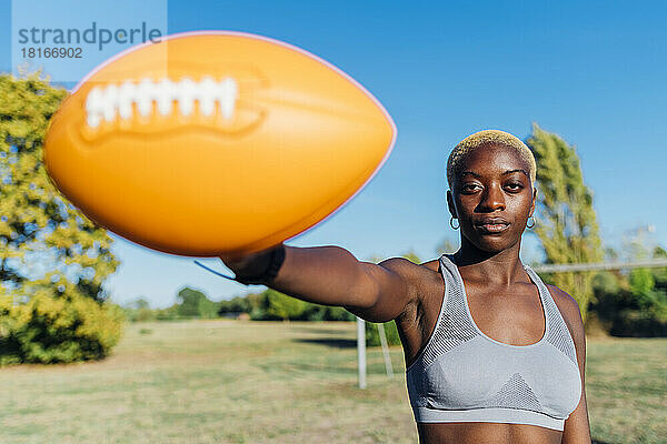 Sportlerin zeigt Ball an sonnigem Tag