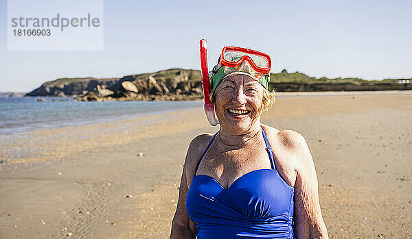 Fröhliche Frau mit Taucherbrille und Schnorchelmaske am Strand