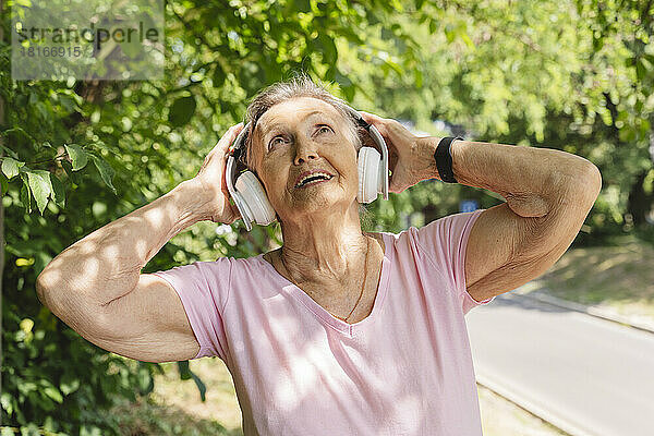 Glückliche ältere Frau  die Musik hört und im Park trainiert