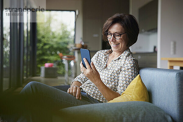 Glückliche ältere Frau  die zu Hause ihr Smartphone benutzt