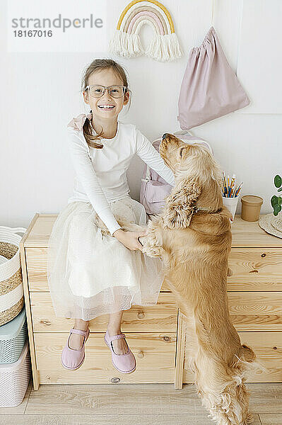 Glückliches Mädchen  das zu Hause mit Hund spielt