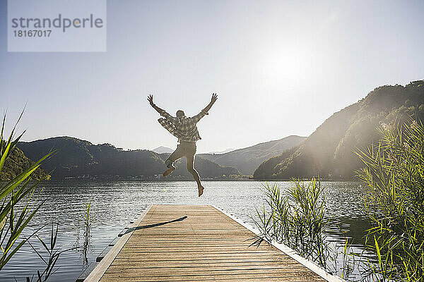 Glücklicher reifer Mann springt auf Steg über See