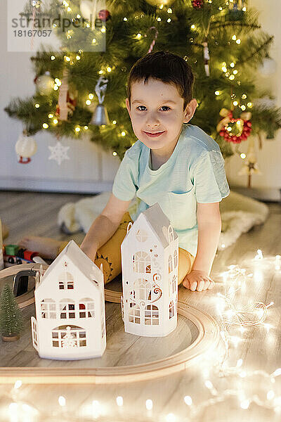 Smiling cute boy playing by Christmas decoration at home