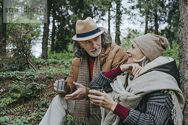 Frau und älterer Mann sitzen im Wald und trinken Tee