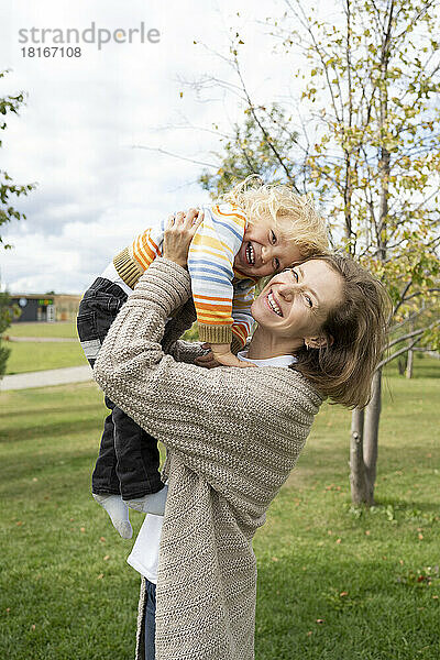 Fröhliche Frau spielt mit Sohn im Park