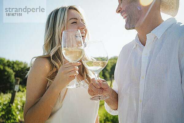 Glückliches Paar stößt an einem sonnigen Tag im Weingut auf Wein an