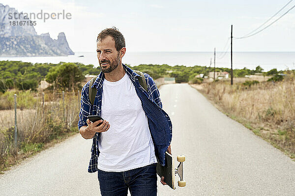 Mann mit Mobiltelefon und Skateboard unterwegs