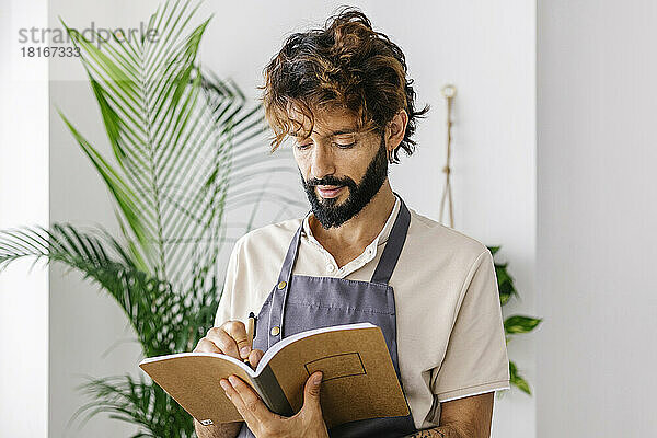 Mann schreibt in Buch im Pflanzenladen
