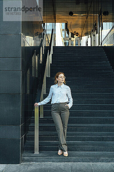 Selbstbewusste Geschäftsfrau mit der Hand in der Tasche auf der Treppe
