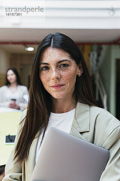 Porträt einer brünetten Geschäftsfrau mit Laptop im Büro