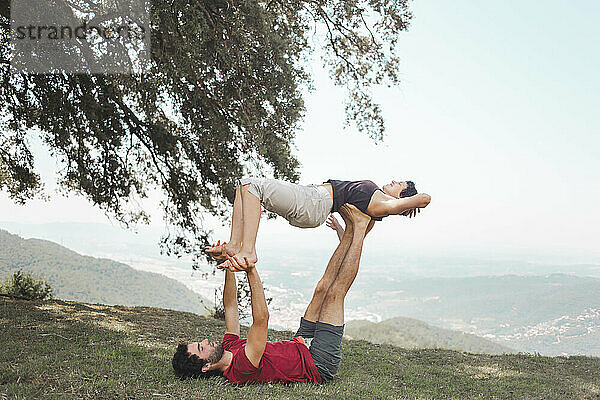 Young couple practicing yoga on mountain top