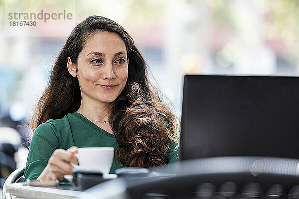 Lächelnder Freiberufler mit Laptop im Straßencafé
