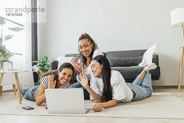 Fröhliche Mitbewohner winken per Videoanruf über den Laptop im Wohnzimmer