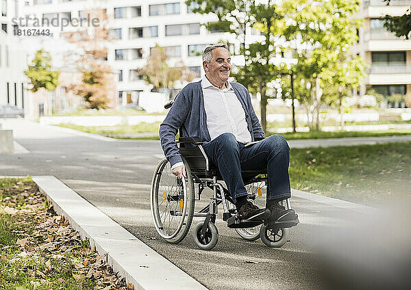 Lächelnder älterer Mann im Pullover sitzt im Rollstuhl