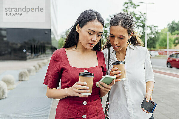 Woman sharing smart phone with friend