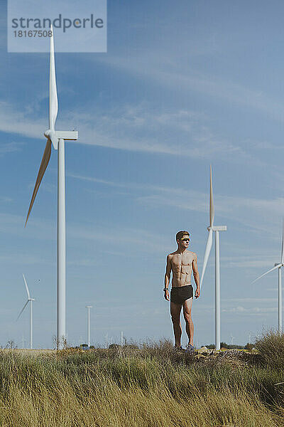 Nackter Oberkörper junger Athlet vor Windkraftanlage