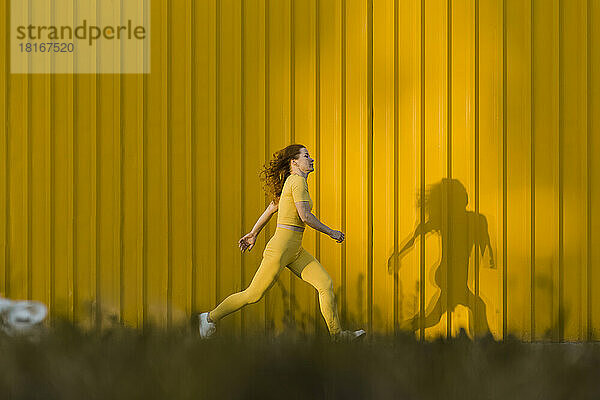 Frau läuft vor gelber Wand