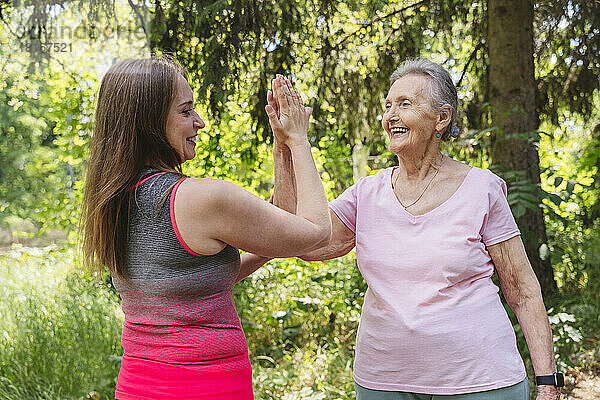 Lächelnder Fitnesstrainer berührt die Hand einer älteren Frau  die im Park trainiert