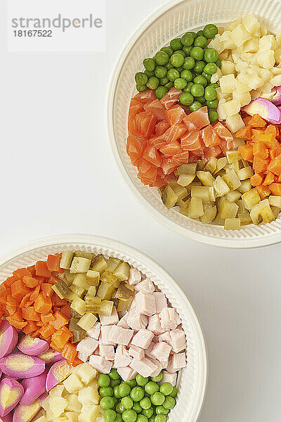 Bowls with Olivier salad ingredients against white background