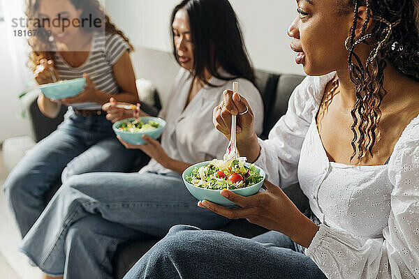 Frau isst zu Hause mit Freunden Salat