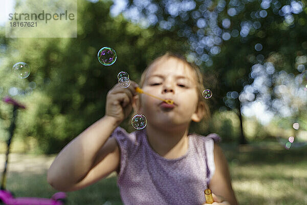 Mädchen bläst Seifenblasen im Park