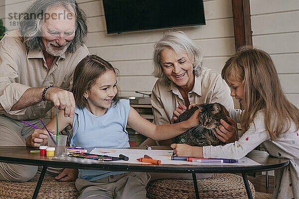 Großeltern und Enkelkinder spielen zu Hause mit der Katze