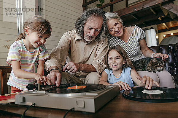 Großvater und Enkelin spielen zu Hause Musik auf einem Vinyl-Plattenspieler