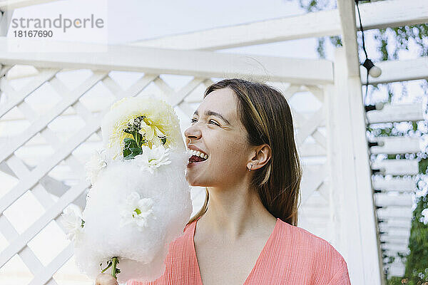 Glückliche Frau  die Zuckerwatte mit Blumen isst