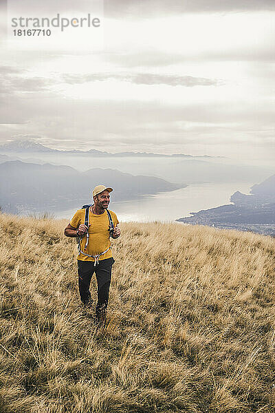 Lächelnder Mann mit Mütze beim Wandern auf dem Berg