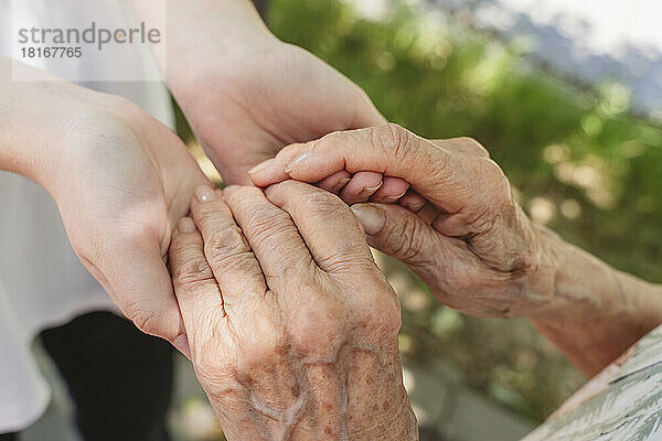 Ältere Frau hält Hände ihrer Urenkelin