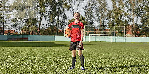 Girl with rugby ball standing on field