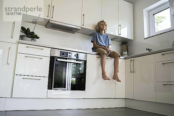 Junge sitzt zu Hause auf der Küchentheke