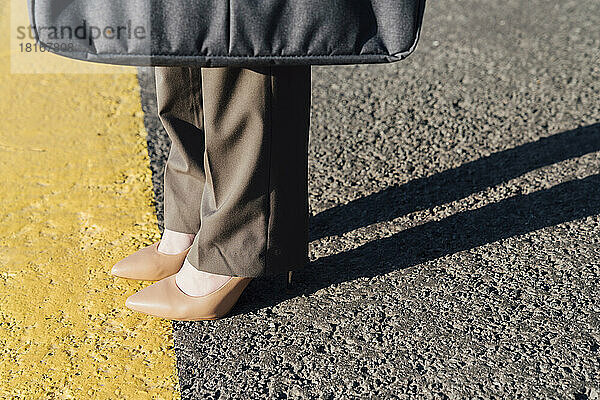 Businesswoman wearing brown stilettos on yellow line