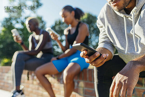 Sportler nutzt Mobiltelefon an sonnigem Tag