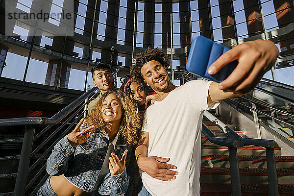 Lächelnde  gemischtrassige Freunde  die am Bahnhof ein Selfie mit dem Handy machen