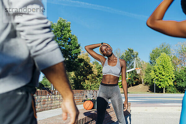Young sportswoman exercising with friends on sunny day