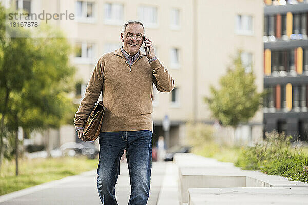 Glücklicher älterer Mann mit Tasche und Telefongespräch