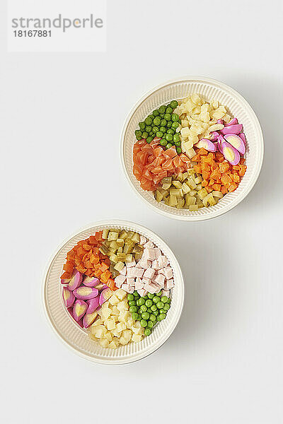 Schüsselset mit frischen Zutaten für Olivier-Salat vor weißem Hintergrund