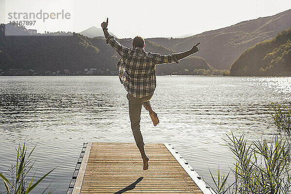 Reifer Mann springt im Urlaub auf Steg über See