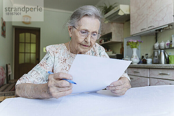 Ältere Frau liest zu Hause Vertragsunterlagen