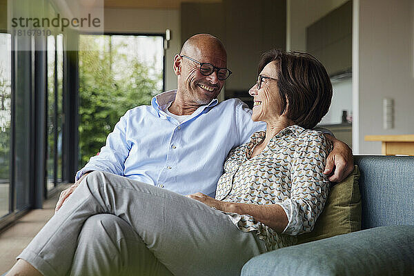 Loving senior couple sitting on sofa at home