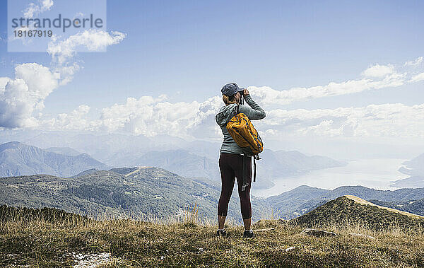 Frau fotografiert mit der Kamera vor Bergen