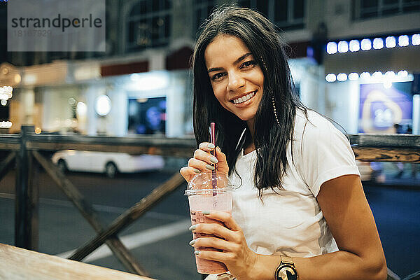 Glückliche schöne Frau mit Smoothie im Straßencafé